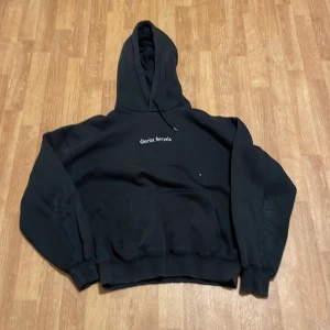 Svart hoodie från District Fortysix - Säljer en svart hoodie från District Fortysix med en cool design på baksidan. Den har en stor ficka fram och en bekväm huva. Perfekt för höst och vinter, och passar till alla casual outfits. Skön och stilren!