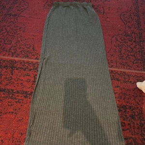 Grå ribbad långkjol - Säljer en superfin grå ribbad långkjol som är perfekt för både höst och vinter. Kjolen har en elastisk midja för en bekväm passform och är gjord i ett mjukt material som håller dig varm. Den är i mycket bra skick och passar perfekt till både vardag och fest. 🖤