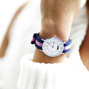 Ny klocka från DM - Snygg klocka från DM med ett randigt armband i blått och rosa. Klockan har en stilren vit urtavla med silverdetaljer och ett minimalistiskt utseende. Perfekt för både vardag och fest!
