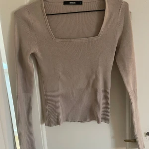 Beige ribbad tröja från BikBok - Säljer en superfin beige ribbad tröja från BikBok i storlek S. Den har en fyrkantig halsringning och långa ärmar, perfekt för både vardag och fest. Tröjan är i mycket bra skick och sitter snyggt på kroppen. Passar perfekt till höst- och våroutfits!