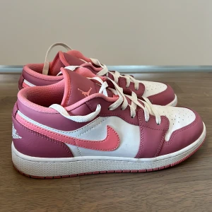 Nike Air Jordans i rosa och vit - Säljer ett par snygga Nike Air Jordans i rosa och vit. De har en klassisk design med snörning och är i mycket bra skick. Perfekta för både vardag och fest! Stor logga på hälen och bekväm passform.