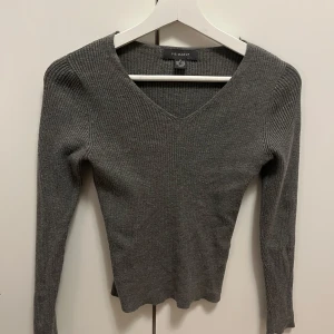 Grå ribbad tröja från Primark - Säljer en stilren grå ribbad tröja från Primark. Den har en v-ringad hals och långa ärmar, perfekt för både vardag och lite finare tillfällen. Tröjan är i mycket bra skick och passar perfekt till höst- och vintergarderoben. Supermysig och lätt att matcha med andra plagg!