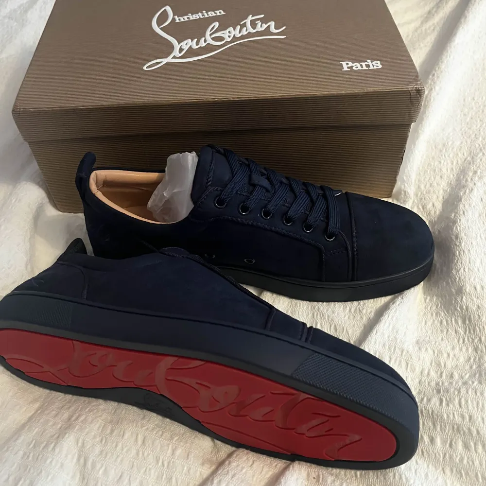 Säljer ett par snygga svarta sneakers från Christian Louboutin i nytt skick. De har den ikoniska röda sulan och är gjorda i skinn. Perfekta för att ge din outfit en lyxig touch. Skorna kommer med originalförpackning och tillbehör.. Skor.