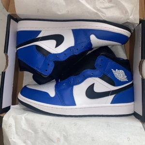 Nike Air Jordan 1 Mid - Säljer ett par Nike Air Jordans i snygg blå och vit o svart färgkombination. Skorna är helt nya. Nypris 1749kr. Vid snabb affär kan priset diskuteras