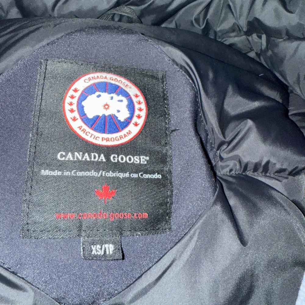 Säljer en svart parkajacka från Canada Goose i mycket bra skick. Jackan har en avtagbar huva med pälsdetalj och är perfekt för kalla vinterdagar. Den har flera praktiska fickor och en broderad logotyp på bröstet. Passar både för vardag och utomhusaktiviteter. Supervarm och stilren! ❄️. Jackor.