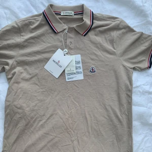 Beige pikétröja från Moncler - Säljer en snygg pique från Moncler i nyskick med taggar och KVITTO. Nypris:3000kr