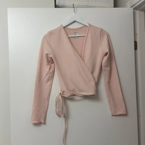 Rosa kofta - Säljer en superfin rosa kofta med knytband i midjan. Den har långa ärmar och är kroppad. Toppen är i bra skick och har en snygg broderad logga på ryggen. Köpt i en dansbutik. Knappt använd