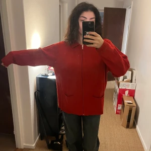 Röd kofta med dragkedja - Säljer en mysig röd kofta med dragkedja framtill. Perfekt för höst och vinter, den har långa ärmar och en bekväm passform. Koftan är i bra skick och passar perfekt för en avslappnad stil. Perfekt för att hålla sig varm och snygg under kyliga dagar!