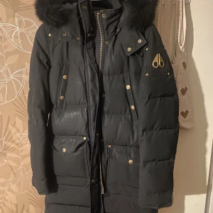 Svart dunjacka från Moose Knuckles - Säljer en snygg svart dunjacka från Moose Knuckles i bra skick. Jackan har en fluffig pälsdetalj på huvan och praktiska fickor med knappar. Behövs kemtvättas. Intresserad? Pris kan diskuteras Kontakta mig 