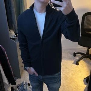 Mörkblå kofta från C&A - Säljer en stilren mörkblå kofta från C&A i mycket bra skick. Den har en dragkedja framtill och är perfekt för både höst och vår. Koftan är långärmad och passar bra till både vardag och fest. Perfekt för dig som gillar en klassisk look!