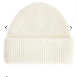 Vit ribbad mössa - Superfin vit ribbad mössa som är perfekt för kyliga dagar. Den är stickad och har en klassisk design som passar till allt. Mysig och stilren, ett måste i vintergarderoben!
