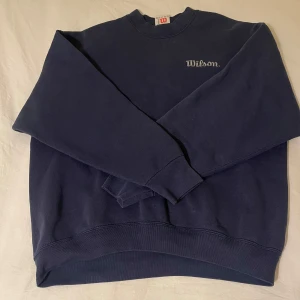 Mörkblå sweatshirt från Wilson - Säljer min mörkblåa sweatshirt från Wilson köpt second hand. Är i storlek L men jag har storlek S och har haft den som en oversized tröja. Liten vit missfärgning under kragen men syns knappt, annars fint skick!