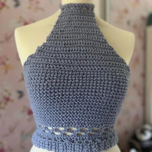 Lilagrå virkad halterneck topp - Superfin lilagrå virkad halterneck topp som är perfekt för sommaren. Den har en unik design med ett snyggt hålmönster vid midjan. Perfekt för en avslappnad dag eller en somrig fest. Passar bra till både jeans och kjol!