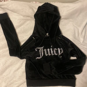 Svart sammetshoodie från Juicy Couture - Säljer en supermjuk och snygg svart hoodie i sammet från Juicy Couture. Den har en glittrig Juicy-logga på framsidan och en bekväm huva. Mjukt och skönt material, nästan helt oanvänd. Den är inte så lång vid magen, men långa armar.