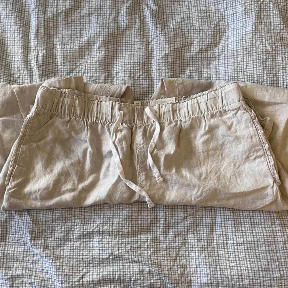 Säljer ett par bekväma beige linnebyxor från H&M i storlek M. De har en elastisk midja med snörning för extra komfort. Perfekta för en avslappnad stil under varma dagar. Byxorna är i bra skick och redo för nya äventyr!. Jeans & Byxor.