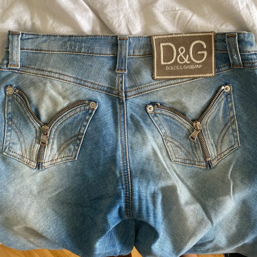 Säljer ett par snygga blå jeans från Dolce & Gabbana. De har en cool design med dragkedjor på bakfickorna och en klassisk femficksmodell. Perfekta för både vardag och fest! Säljer då de är lite för korta på mig (är 165 för referens) . Jeans & Byxor.