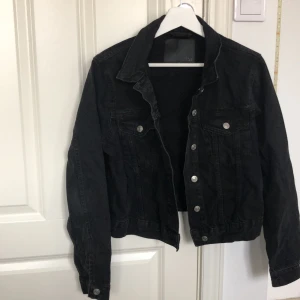 Svart jeansjacka från 157 - Säljer en svart jeansjacka från 157 i storlek S. Jackan har en klassisk design med knappar framtill och två bröstfickor. Perfekt för vår och höst, och ger en cool look till vilken outfit som helst. Inte använd men lite skrynklig annars i bra skick!