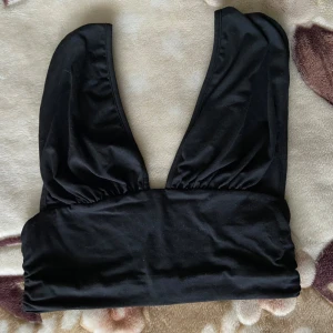 Svart halterneck-topp från SHEIN, stl. S - Mycket fint skick  - Svart färg. Halterneck-topp. Djup V-ringning. Tjocka axelband. Elastiskt band vid bysten. Figursydd. Figurnära. Luftigt material. Stretchig. Passar större byst, blir mycket löst annars. Storlek: S. Skick: Mycket fint. Kom privat för måtten då de inte får plats! 