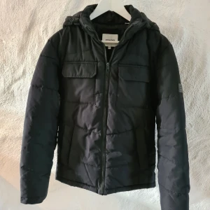 Svart vinterjacka från Jack and jones stl xs  - Säljer en svart vinterjacka från Jack and jones i bra skick. Jackan har en dragkedja framtill och en mysig huva. Perfekt för kalla höst- och vinterdagar. Den har fickor i sidorna  och 2 bröstfickor med lock. Passar både till vardags och lite mer uppklädda tillfällen.