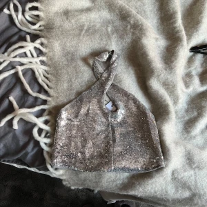 Glittrig paljettopp från Gina Tricot - Säljer en superfin glittrig topp från Gina Tricot i storlek M. Toppen är täckt med silverpaljetter och har en halterneck-design med knäppning i nacken. Perfekt för festliga tillfällen när du vill glänsa lite extra! ✨ är oanvänd med lappen kvar✨