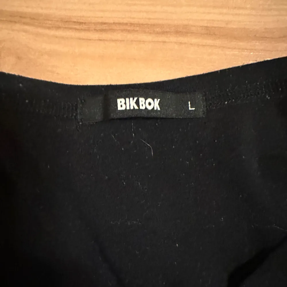 Säljer en svart croppad tröja från Bik Bok i storlek L. Den har långa ärmar med vita ränder längs sidorna, vilket ger en sportig look. Perfekt för en casual dag eller en avslappnad kväll med vänner. . Neuletakit & Villapaidat.