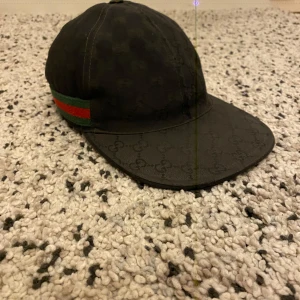 Gucci keps svart - Svart gucci keps storlek S har bara en liten skada, skriv för fler bilder. Formen är fortfarande bra och stadig. Gamla modellen så formen sätter sig finare. Priset är ej hugget i sten möts i Stockholm eller fraktar.