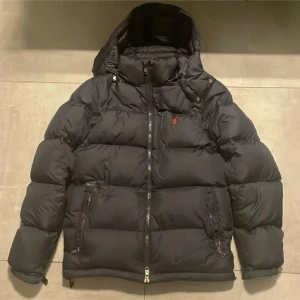 Mörkblå dunjacka från Polo Ralph Lauren🔵 - Säljer en snygg mörkblå dunjacka från Polo Ralph Lauren hyfsat bra skick. Riktigt fet jacka som passar bra inför vinter. Skriv om ni har frågor. Har haft hål vid fickan som är lagat.