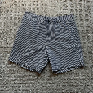 Randiga shorts från These Glory Days - Snygga randiga shorts från These Glory Days i storlek 52. De är svartvita med en knapp och dragkedja fram. Perfekta för sommaren med en stilren look. Passar både till vardags och lite mer uppklädda tillfällen.