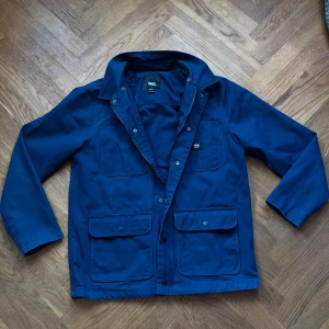 Navy Field Jacket - Säljer en snygg field jacket från Vans i mycket bra skick.  Perfekt för höst och vår, och passar till både vardag och fest. Jackan är långärmad och gjord i ett slitstarkt material. Hör av dig vid frågor👋