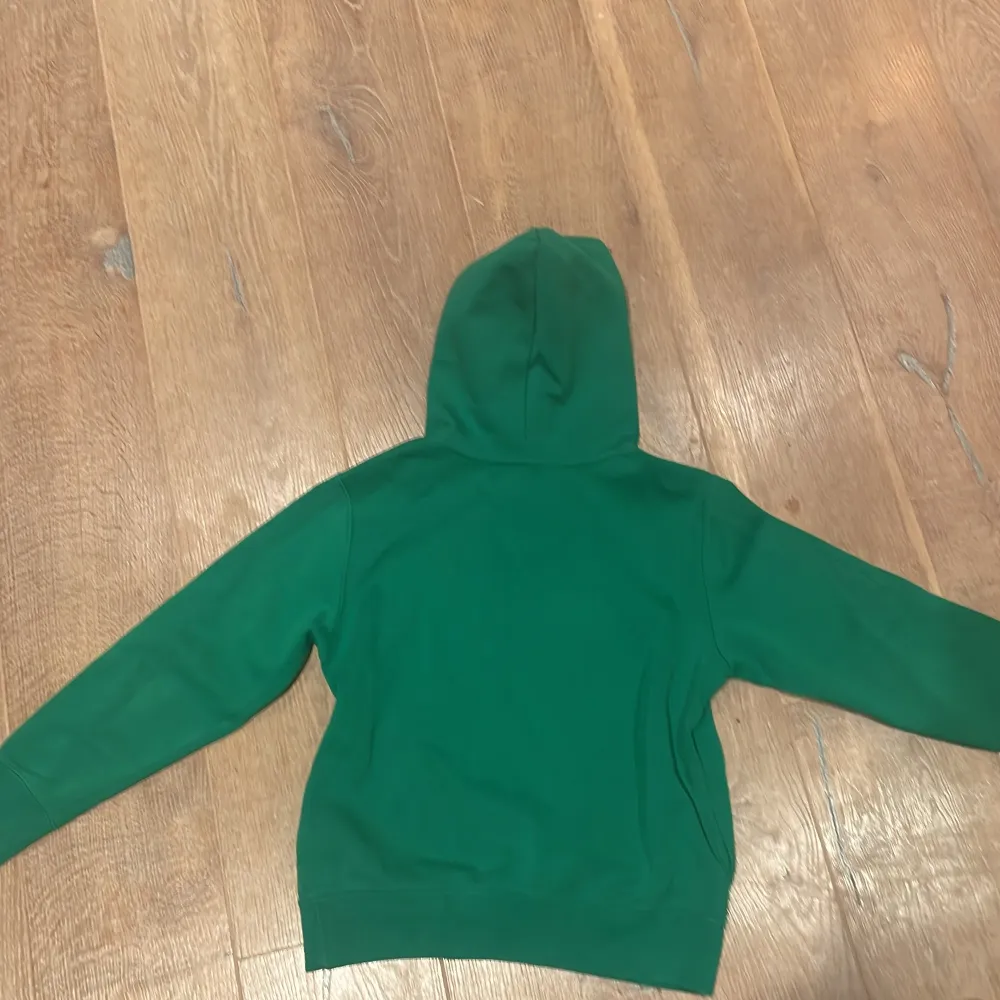 Säljer en snygg grön hoodie från Ralph Lauren med stor gul POLO-text på framsidan. Den har en klassisk broderad logga i blått på bröstet. Perfekt för en avslappnad stil och passar bra till både höst och vår. Skön och bekväm att ha på sig!. Tröjor & Koftor.