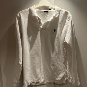 Vit pikétröja från Ralph Lauren - Säljer en klassisk vit pikétröja från Ralph Lauren. Den har långa ärmar och den ikoniska loggan broderad på bröstet. Perfekt för en stilren och avslappnad look. Passar både till vardags och lite finare tillfällen .Storlek L men är som en M ( får ej på mig den därav ingen fitpic. Tröjan passar den person som har stor S eller M 