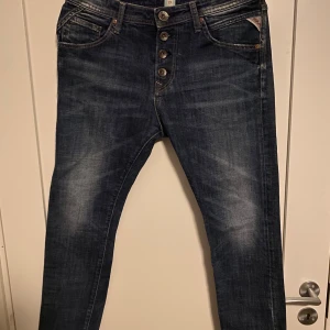 Mörkblå jeans från Replay - Säljer ett par snygga mörkblå jeans från Replay i storlek 27. De har en klassisk femficksdesign med knappar framtill och coola sömmar på bakfickorna. Perfekta för både vardag och fest! 🕺