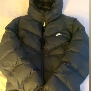 Svart pufferjacka från Nike - Säljer en svart pufferjacka från Nike i bra skick. Jackan är perfekt för vintern, den har en dragkedja framtill och en hög krage