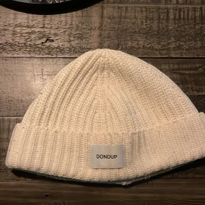 Vit stickad mössa från Dondup - Säljer en superfin vit stickad mössa från Dondup. Den är perfekt för kalla dagar och har en snygg ribbad kant. Mössan är i one size och passar de flesta. Köpte denna av en kompis men säljer den igen för den va för stor. Nu är den redo att hålla dig varm och stilren i vinter!