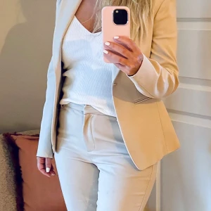 Beige kavaj och byxor - Säljer en stilren Tiger beige kavaj med matchande byxor. Perfekt för både kontoret och festliga tillfällen. Kavajen har en klassisk passform och byxorna är bekväma med en normal passning i stl 36. använd vid ett tillfälle. 