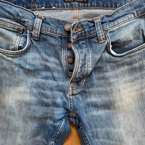 Nudie Grim Tim blå jeans - Nudie Grim Tim jeans i mycket fint skick.  Storlek: 30 31 Tvätt: Pale shelter Köpte dem förra sommaren på Nudie i Malmö men har inte kunnat ha dem för de var för stora i midjan för mig. Nudie sydde in knappen en cm men det gjorde ingen skillnad. 