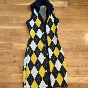 Rutig klänning  - En gul/vit/svart rutig klänning med svarta knappar - oanvänd 