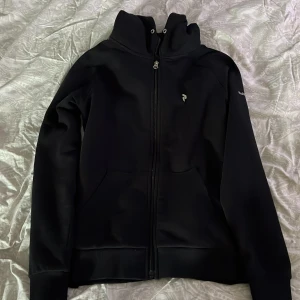 Svart jacka från Peak Performance - Säljer en snygg svart tröja från Peak Performance. Den är i bra skick men saknar snöre 