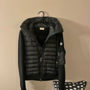 Moncler Hooded Cardigan  - Svart moncler cardigan med luva. Den är liten i storlek så den passar bra som M men den är storlek L.   Cond - 7/10! Inga håll eller sådant, lite små slitage möjligtvis 