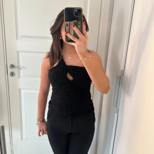 Svart oneshoulder topp - Snygg svart oneshoulder topp med en cool twistdetalj framtill. Den är tight och har en rynkad design. As cool och fin att ha på en fest🤗 kontakta mig om du har några frågor💖