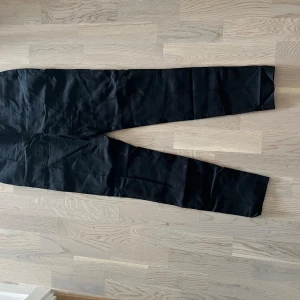 Svarta kostymbyxor - Säljer ett par svarta kostymbyxor. De är i bra skick och perfekta för både formella och semi-formella tillfällen. Byxorna har en klassisk rak passform och är tillverkade i ett bekvämt material som känns skönt mot huden. Perfekta för höst och vinter!