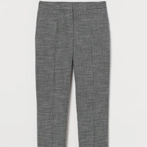 Grå rutiga kostymbyxor - Säljer ett par stiliga grå kostymbyxor med ett klassiskt rutigt mönster. Byxorna har en rak passform och är perfekta för både kontoret och mer formella tillfällen. De är tillverkade i ett bekvämt material som ger en snygg och professionell look. Kommer tyvärr inte längre till användning.