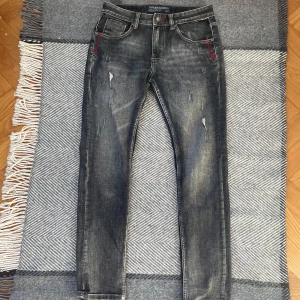Gråa jeans med slitningar  - Säljer dessa feta jeans med slitningar och lite röda detaljer, skriv om du har några frågor!