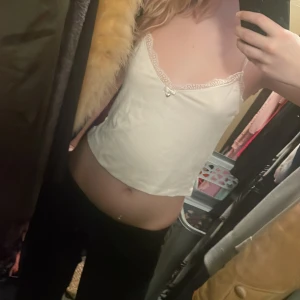 Vit ribbad linnetopp med spetsdetaljer - Säljer en söt vit ribbad linnetopp från Censored. Toppen har spetsdetaljer vid halsringningen och en liten rosett med ett hjärta framtill. Perfekt för en somrig look!