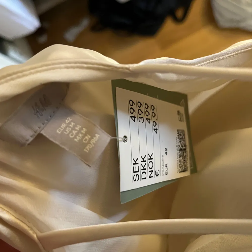 Krämvit långklänning från H&M i ett glansigt material. Klänningen har en stilren design med one shoulder-design som går över till två smala band i ryggen. Perfekt för en speciell kväll eller festlig tillställning. ✨ Denna är helt oanvänd, endast testad en gång! Storlek 42. Mekot.