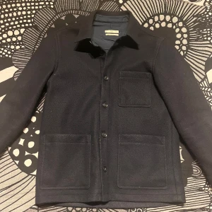 Svart overshirt från MNG - Snygg svart overshirt från mango med regular fit. Jackan har knappar framtill och tre praktiska fickor. Perfekt för lager-på-lager under höst och vår. En stilren och mångsidig jacka för alla tillfällen.