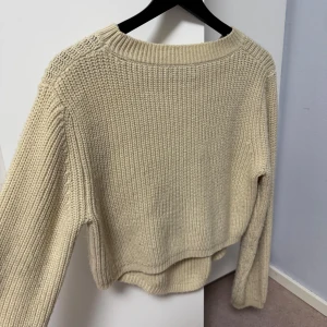 Beige stickad tröja - Säljer en mysig beige stickad tröja med långa ärmar. Perfekt för kyliga dagar och enkel att matcha med olika outfits. Tröjan har en klassisk rund hals och ribbade kanter för extra komfort.