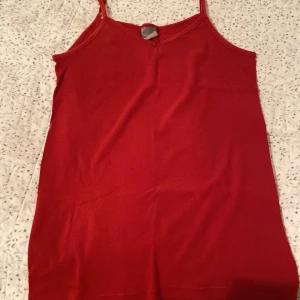Röd linnetopp från Classic - Säljer en enkel och stilren röd linnetopp från Classic. Toppen har smala axelband och en mjuk, bekväm passform. 