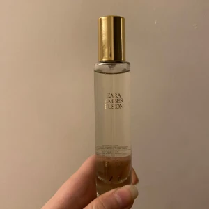 Zara Amber Fusion Parfym - Elegant parfym från Zara i en smal, genomskinlig glasflaska med gyllene lock. Doften Amber Fusion ger en varm och inbjudande känsla. Perfekt för den som älskar en sofistikerad och tidlös doft. Knappt använd🤍 här kommer lite om parfymen för er som är intresserade:  ”Eau de parfum där citrusfriskheten från bergamott och mandarin blandas med marina noter för en bländande introduktion och en glädjefylld smidighet som spelar på de färgglada och syrliga nyanserna från röda bär.”💕