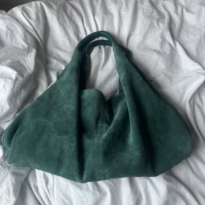 Liebeskind Berlin mockaväska - Snygg mörkgrön axelväska i mocka från Liebeskind Berlin. Väskan har en praktisk dragkedja och en stilren design. Den mjuka mockan ger en lyxig känsla. Jag köpte den från Zalando för 3399kr och är knappt använd😊